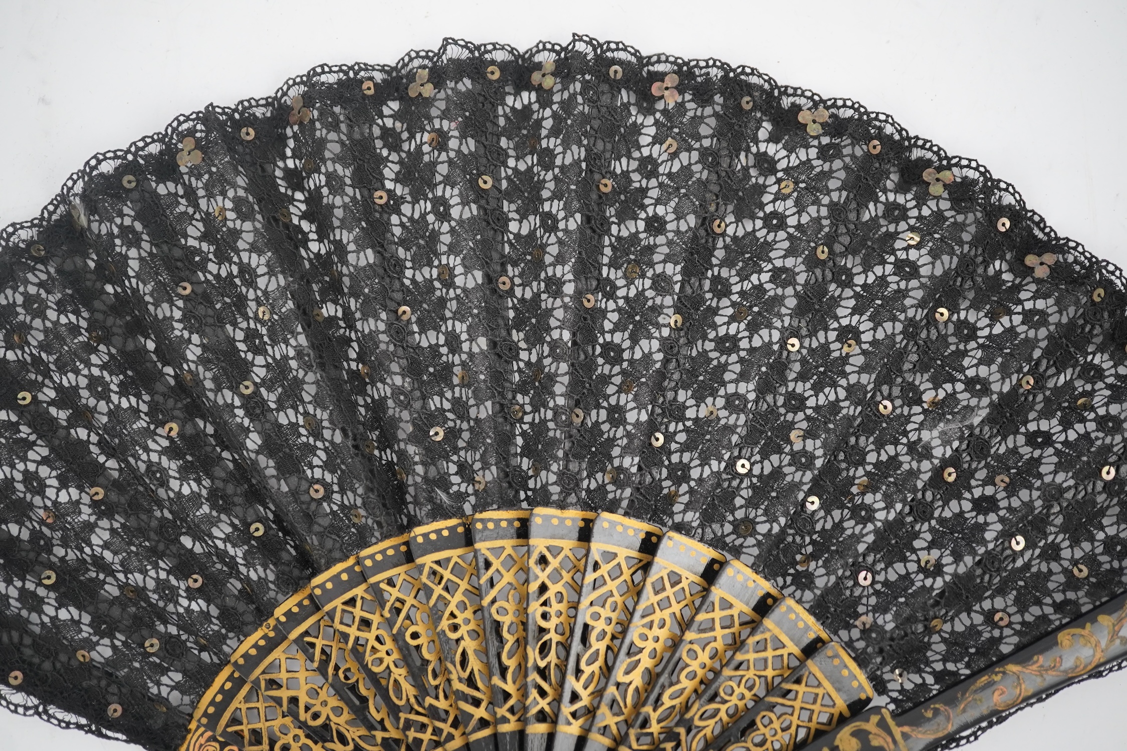 Three novelty fans with a mixed Brussels lace fan and black lace fan, a small language of love in flowers fan, a paper windmill advertising French Café fan, a carved cream Bakelite fan, a black and gilt, lace and sequin